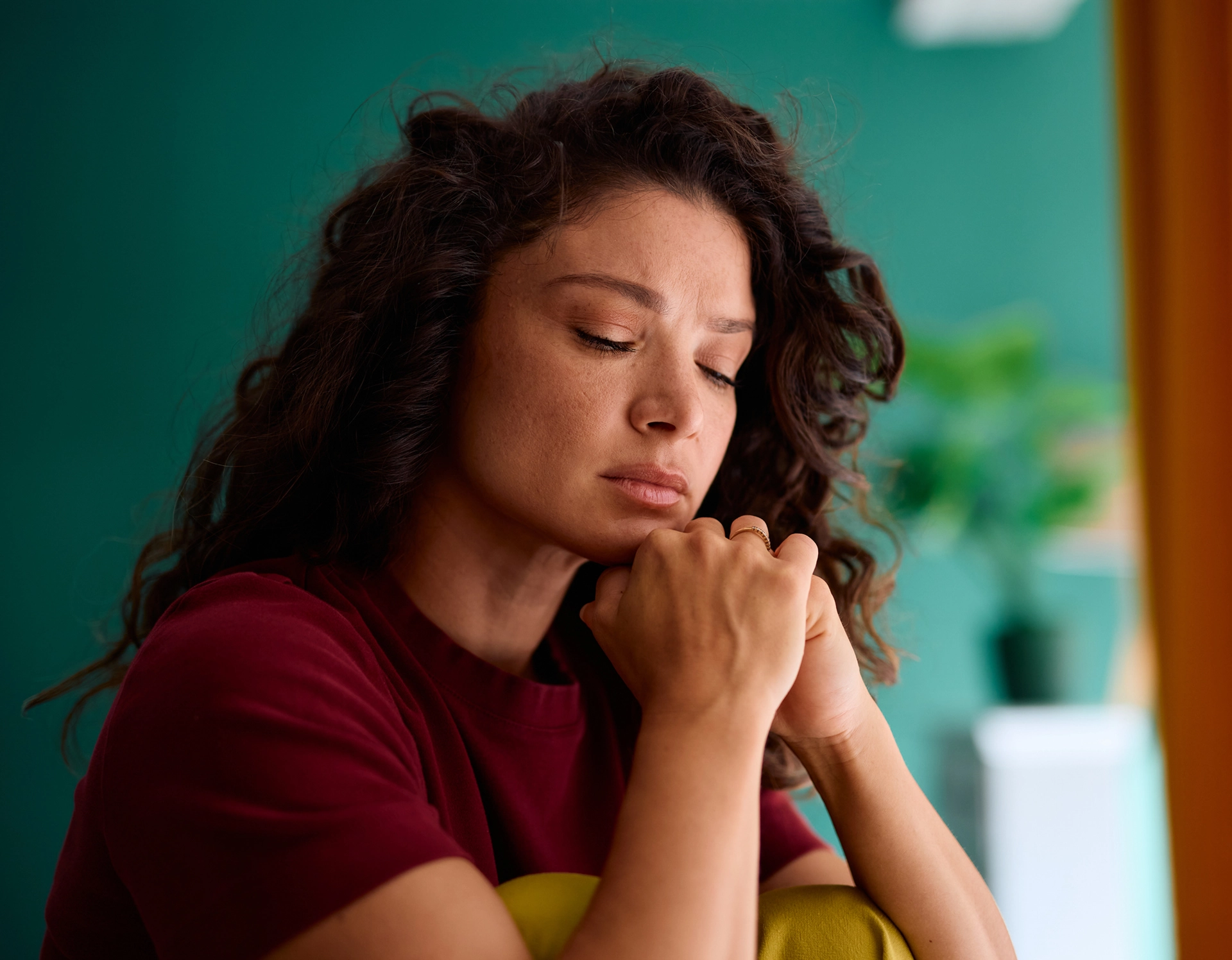 Woman sitting with eyes closed, indoors.
