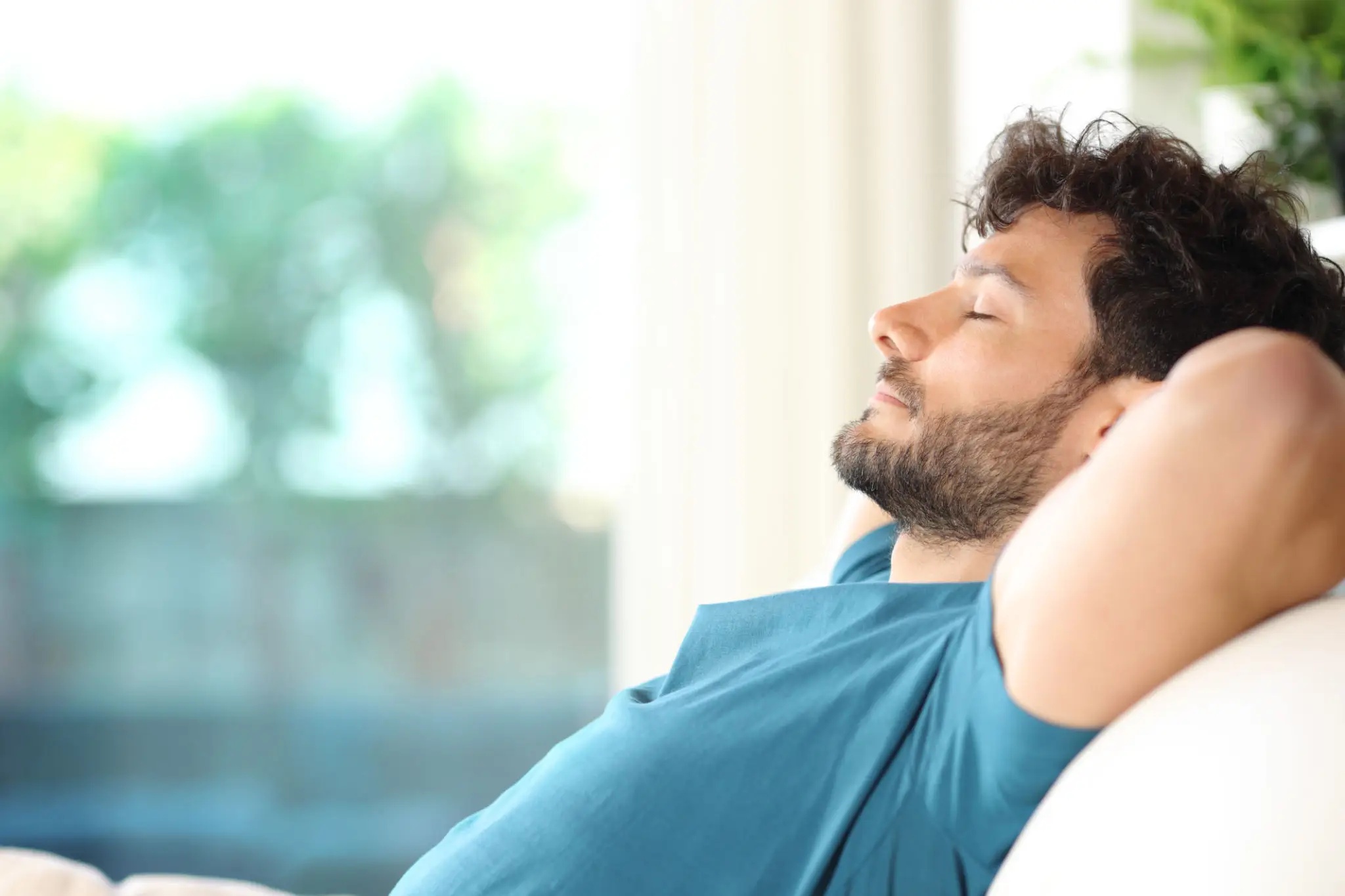 Man reclining on sofa, eyes closed